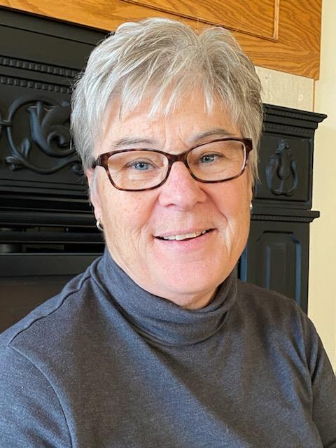 Denise Fandel headshot, with short hair and dark glasses wearing a turtleneck.